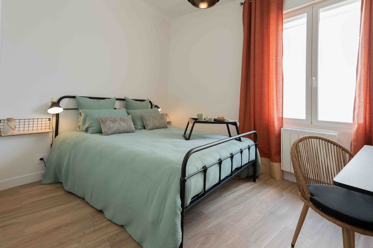 Una camera da letto con un letto, comodino, lampada e finestra con tende.