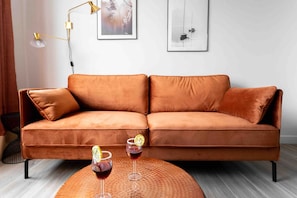 A modern living room with a brown leather sofa, two drinks on a round table, and artwork on the wall. - La Perle Verte - Large air-conditioned 2-bed flat, Agde centre (Agde)