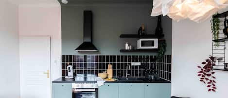 Une cuisine moderne dotée d’un îlot central, d’un four à micro-ondes et d’une hotte noire.