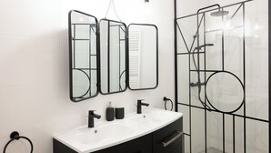 Une salle de bain moderne avec un meuble-lavabo noir, un lavabo blanc et une cabine de douche en verre.
