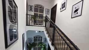 A staircase with black railings, white walls, and framed artwork. - Decorum Apartments (Abuja)