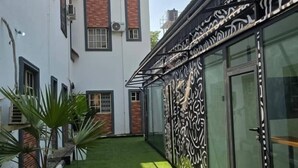 A modern building with a white facade, a brick section, and a glass door with intricate black patterns. - Decorum Apartments (Abuja)