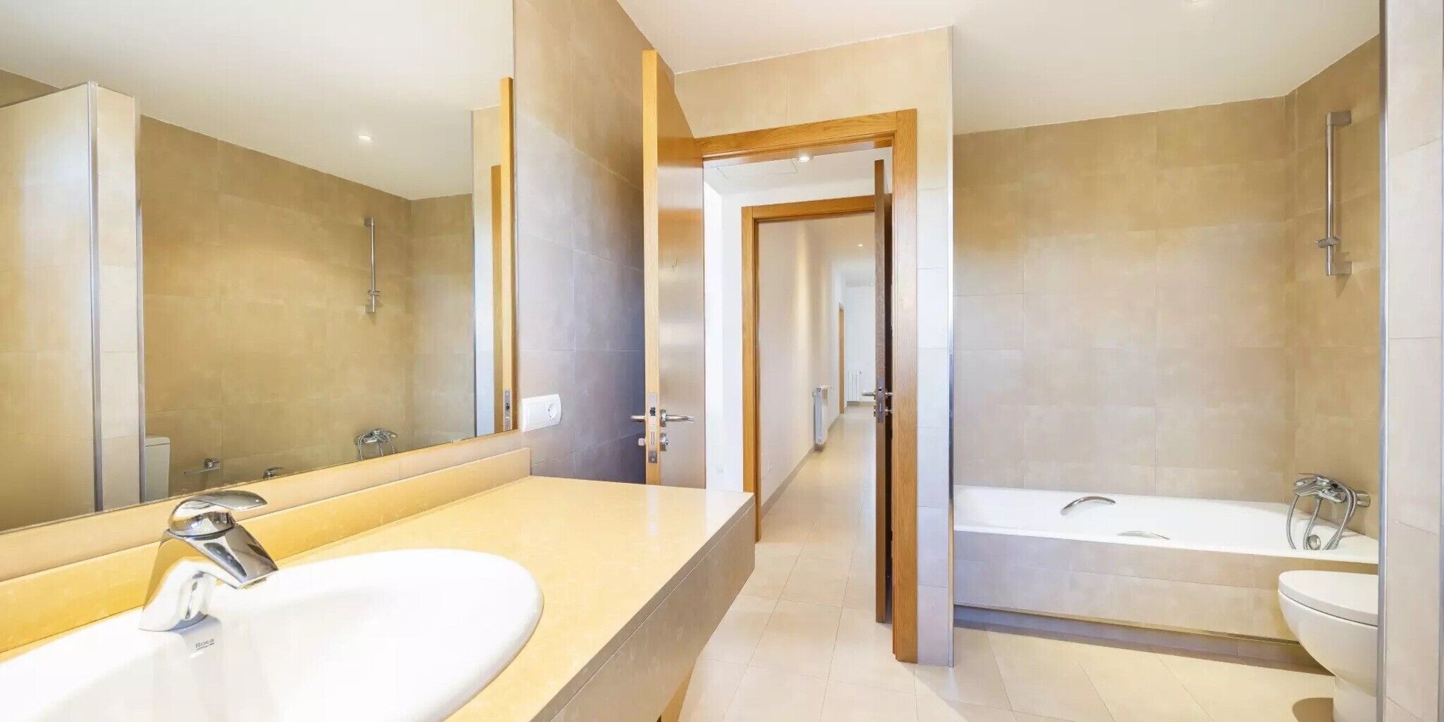 Une salle de bain moderne avec un grand miroir, un lavabo, une baignoire et une douche.