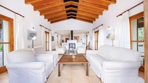A spacious living room with white sofas, a wooden coffee table, and a fireplace. - Country House 'Son Aladern' with Mountain View, Wi-Fi and Air Conditioning (Illes Balears)