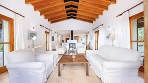 Ein geräumiges Wohnzimmer mit weißen Sofas, einem Holztisch und einem Kamin.