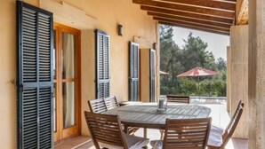 An outdoor patio with a round table and chairs, wooden shutters, and a view of greenery. - Country House 'Son Aladern' with Mountain View, Wi-Fi and Air Conditioning (Illes Balears)