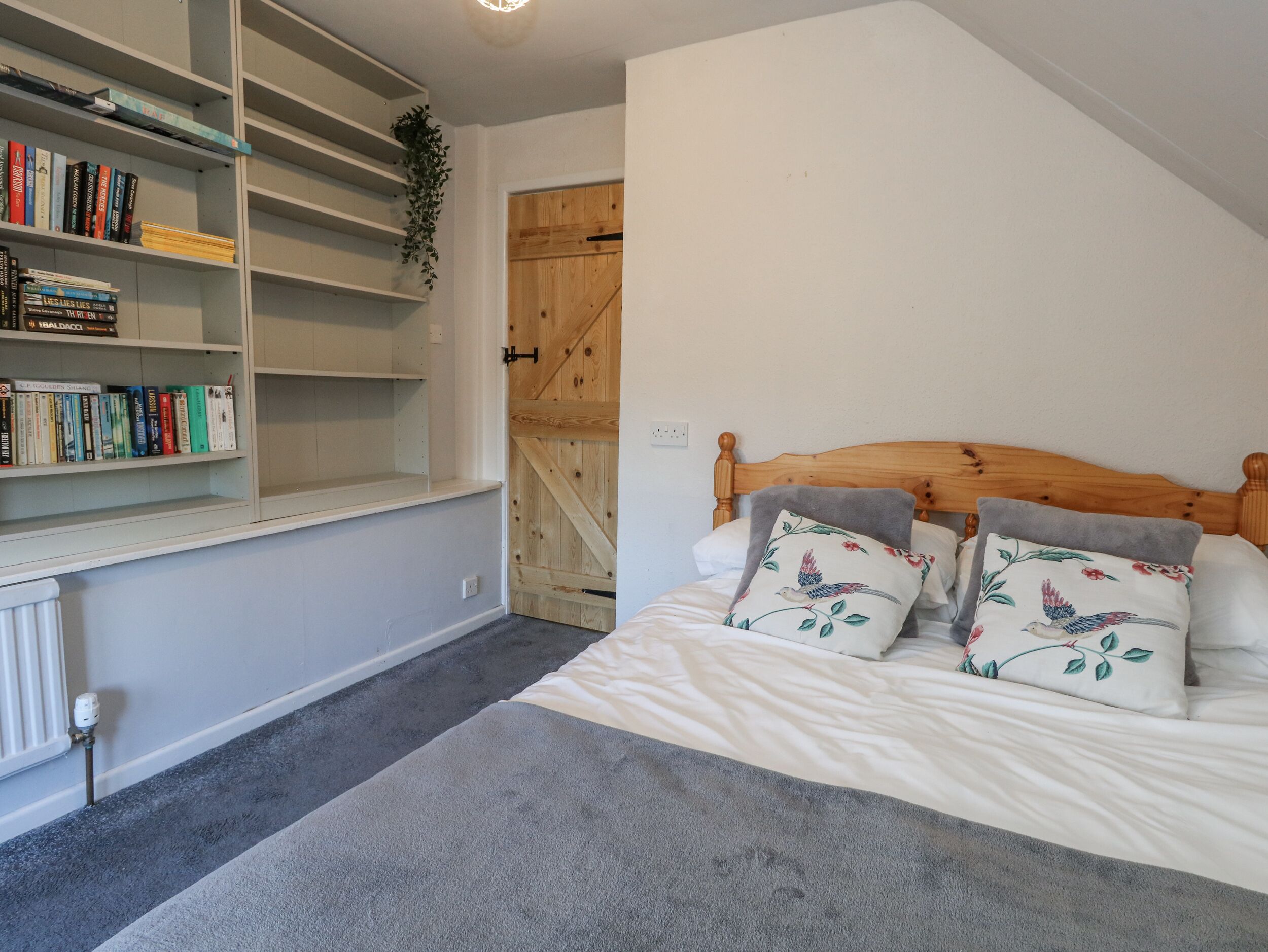 A bedroom with a bed, a bookshelf, and a wooden door.