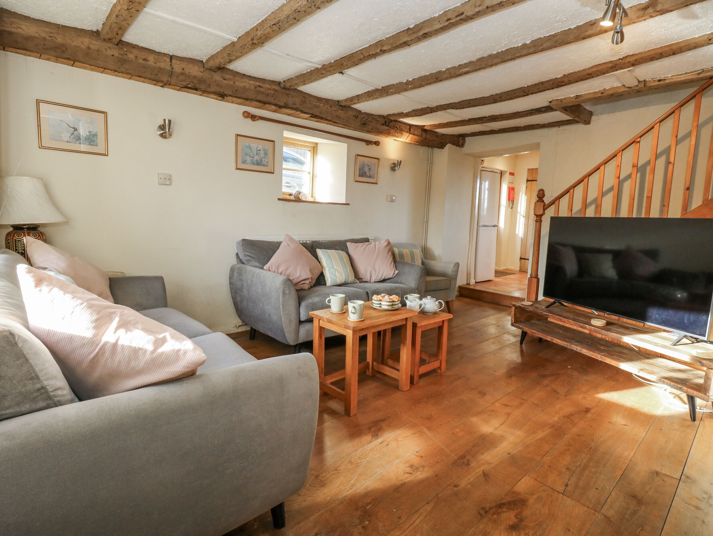 A cozy living room with a sofa, a coffee table, and a TV on a wooden stand.