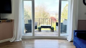 Un salon doté d’une grande porte-fenêtre coulissante donnant sur une terrasse extérieure.