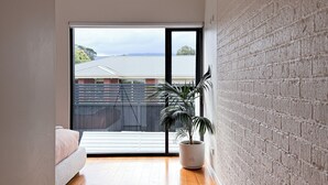 Un interior moderno con suelo de madera, un ventanal grande y una planta en maceta.