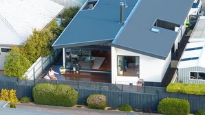 Una casa moderna con techo inclinado, una chimenea visible y un pequeño balcón.