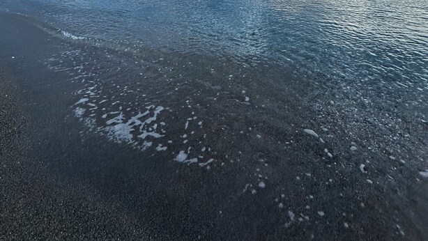 Une plage à l’eau claire, sous un ciel nuageux.