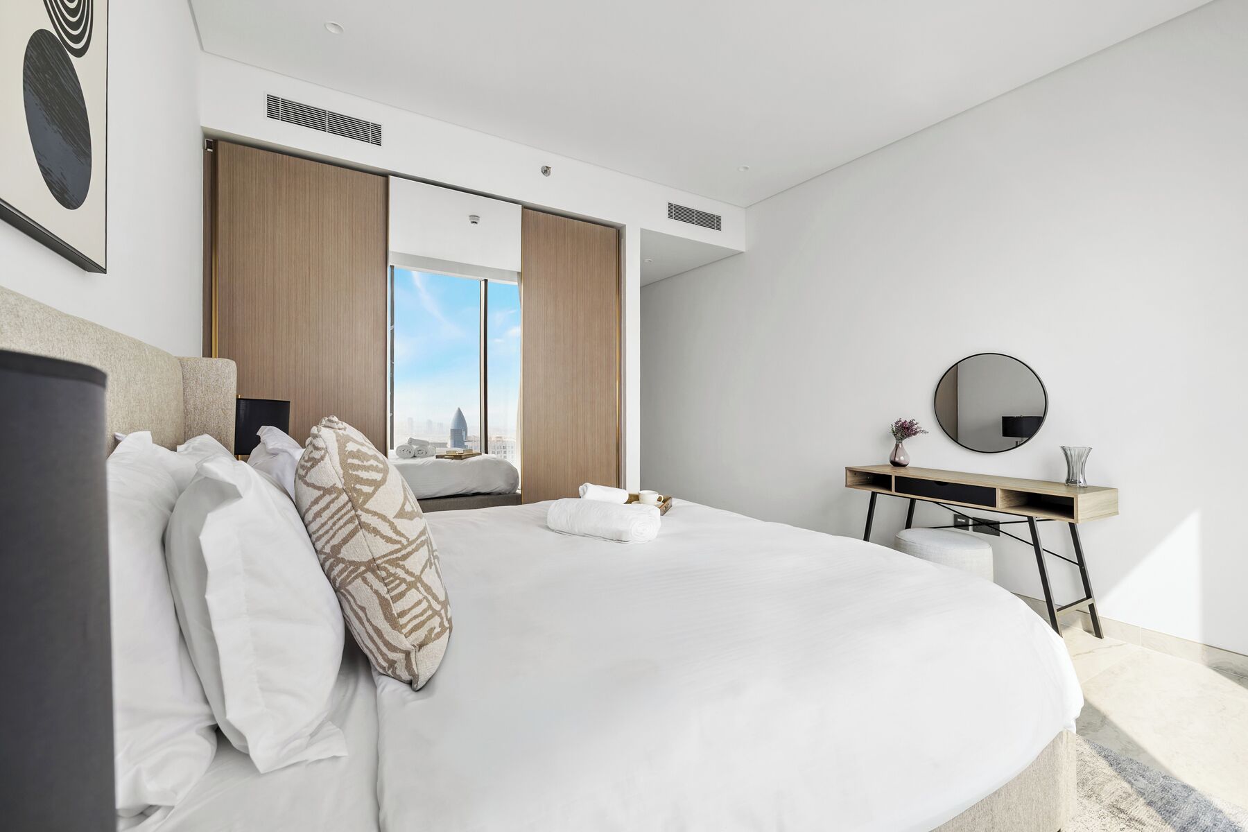Een moderne hotelkamer met een groot bed, een bureau en uitzicht op de stad.