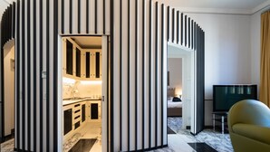 Ett modernt hotellrum med ett litet kök, en tv och en sittgrupp.