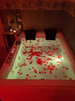 Eine Badewanne voller Rosenblätter und eine Flasche Champagner.