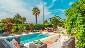 A pool area with lounge chairs, a dining table with food, and lush greenery. - Villa La Vidas by Villas Guide (Medulin)