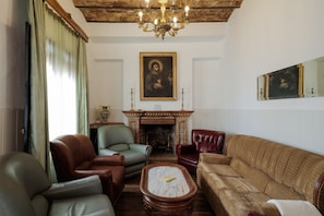 Un soggiorno con divani in pelle, un camino e un lampadario.