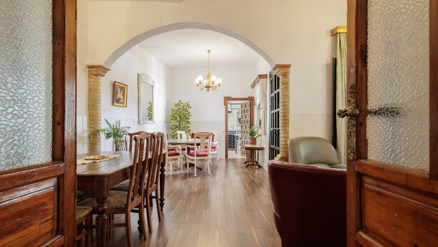 A wooden dining area with a chandelier, a red armchair, and a bookshelf in the background. - Country House 'El Rincón Del Comendador' with Shared Terrace, Wi-Fi and Air Conditioning (Sevilla)