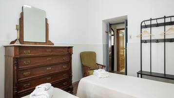 Een hotelkamer met twee bedden, een houten dressoir met lades, een stoel, een spiegel en een kapstok.