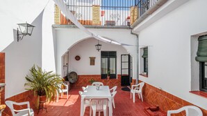A courtyard with a white table and chairs, a potted plant, and a tiled floor. - Country House 'El Rincón Del Comendador' with Shared Terrace, Wi-Fi and Air Conditioning (Sevilla)