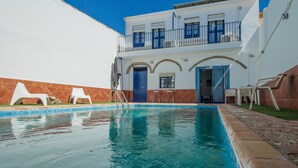 A swimming pool with lounge chairs, a two-story building with balconies, and a clear blue sky. - Country House 'El Rincón Del Comendador' with Shared Terrace, Wi-Fi and Air Conditioning (Sevilla)
