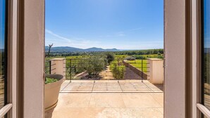 Un balcón con vista a un viñedo y montañas lejanas.