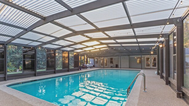 Una piscina interior amb vistes clares als voltants, incloent un porxo cobert i una paret de maó.