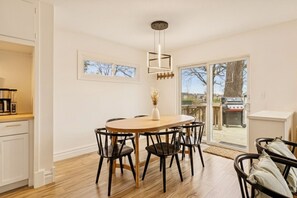 Een eetruimte met een ronde tafel, zwarte stoelen en een hanglamp.