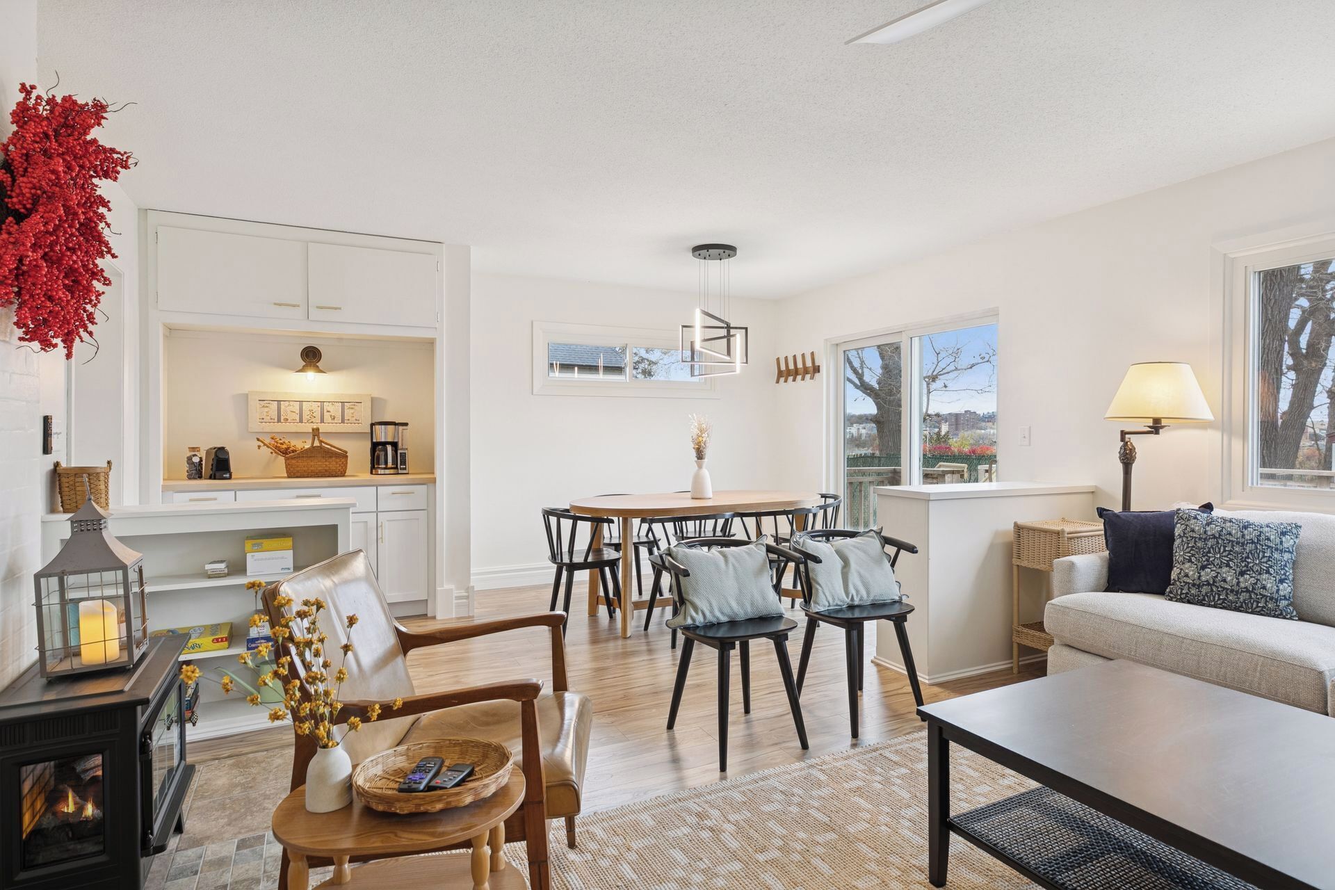 Una sala de estar moderna con chimenea, un comedor con una mesa redonda y sillas, y un sofá con una lámpara.