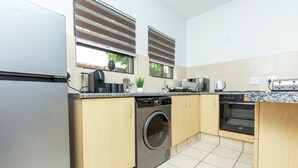 Une cuisine compacte équipée d’un lave-linge, d’un four et d’un lave-vaisselle encastré.