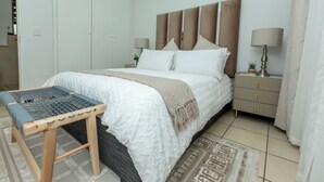 Une chambre à coucher bien rangée, avec un lit, des tables de chevet et un banc.