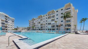 A swimming pool surrounded by a tiled deck, with a multi-story building in the background. - Leonardo Arms 623 Beachfront 2B/2B Vacation Condo! Panoramic Gulf View! (Fort Myers Beach)