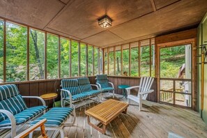Un espace extérieur abrité, doté d’un plancher en bois, de chaises rembourrées à rayures et d’une table en bois.