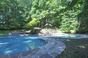 A swimming pool with a stone border, surrounded by a stone wall and a stone deck. - Skyefall Mountain Retreat: Hot Tub, Fire Pit & Wooded Views | Great for Families (Berkeley Springs)