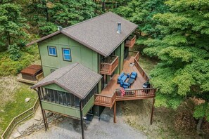 Een chalet met twee verdiepingen, een terras, een overdekte veranda en een klein zitgedeelte buiten.