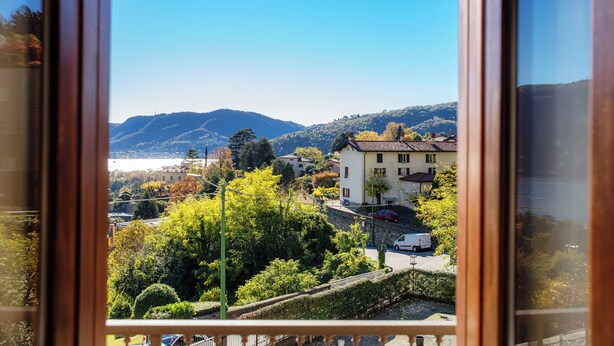 Vista desde una ventana con vistas a una zona residencial, casas, árboles y montañas al fondo.