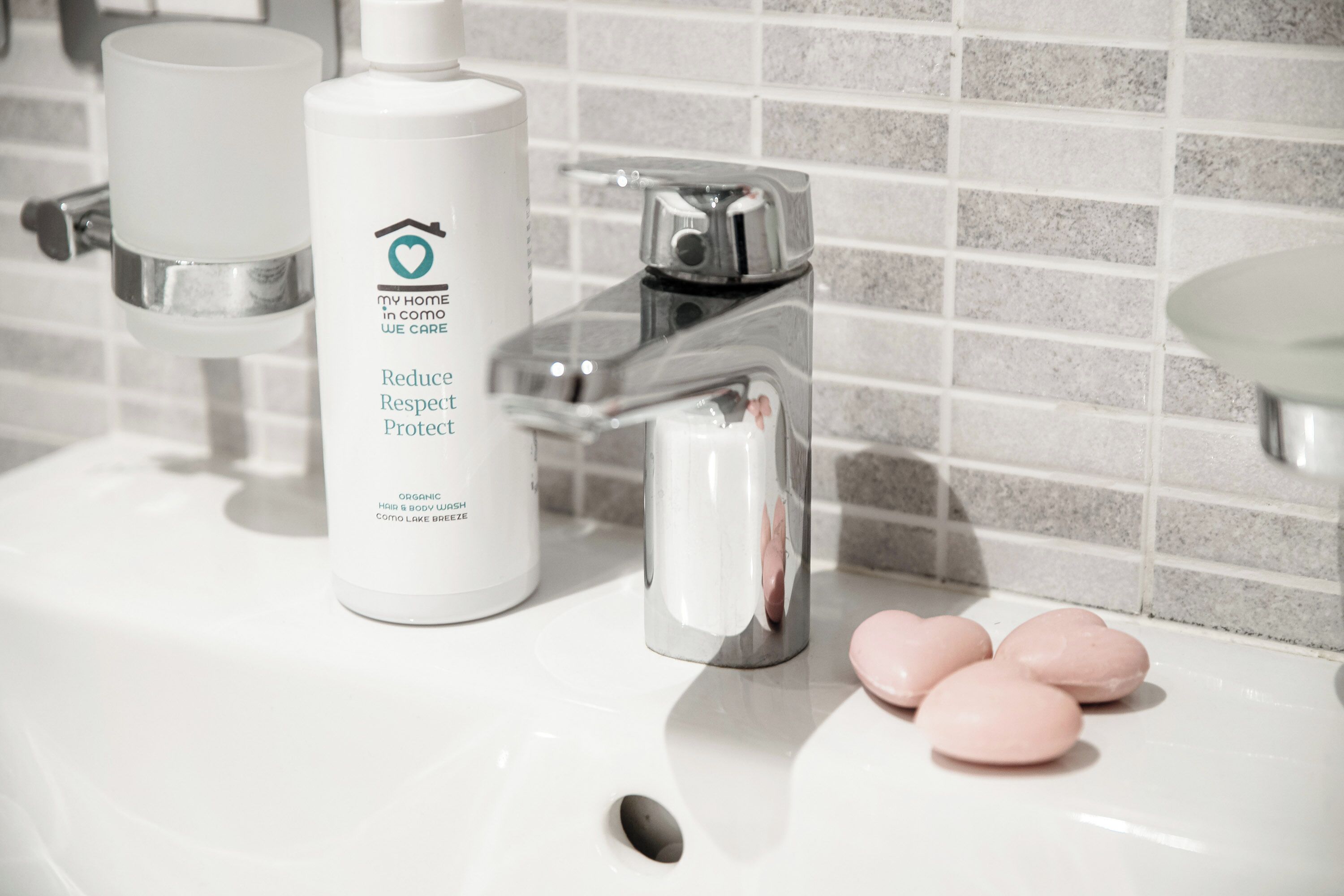 A bathroom sink with a white soap dispenser and a bottle of organic body wash.