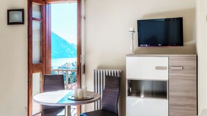Una habitación con una mesa y sillas, un televisor en la pared y vistas al exterior.