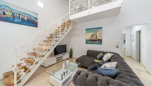 A modern living room with a staircase, a sofa, a coffee table, and artwork on the walls. - Villa Shaula 2 by Villas Guide (Sibenik)