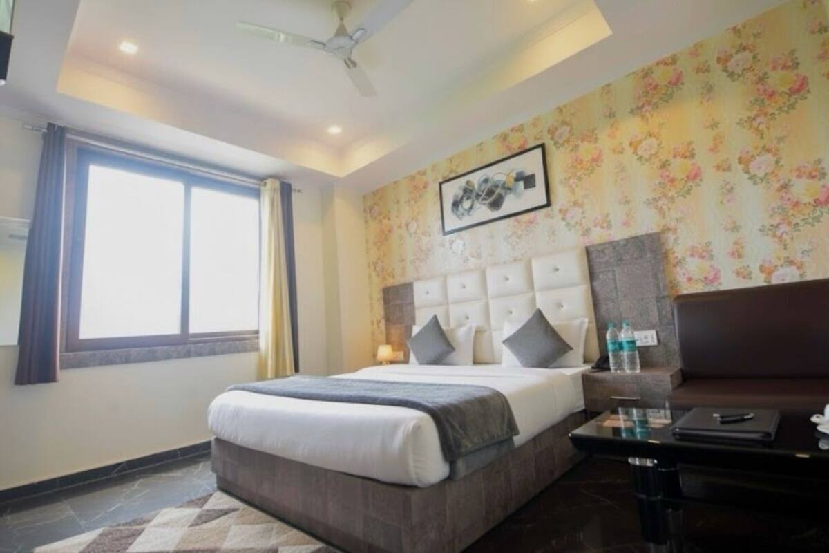 Quarto de hotel com uma cama grande, um sofá, uma mesa de escritório e uma janela.