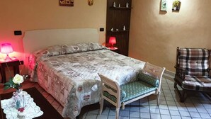 Ein Schlafzimmer mit einem Bett, einem Sessel, einem Nachttisch, einer Lampe und einem kleinen Tisch mit einer Vase.