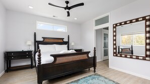 A bedroom with a dark wooden bed, a nightstand, a mirror, and a ceiling fan.