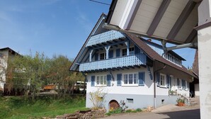 Una casa a due piani con un balcone, un muro in pietra e un giardino.