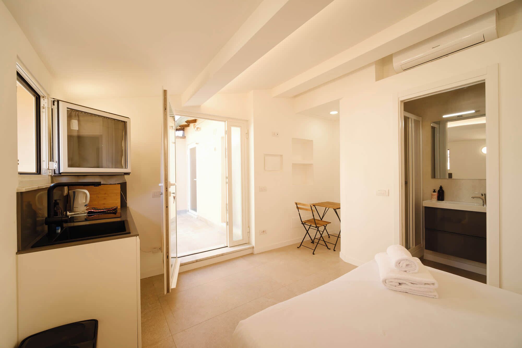 Habitación de hotel con cama, televisión, escritorio, silla y baño con espejo y lavamanos.