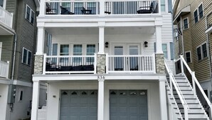 Een woonhuis met twee verdiepingen, een voortuin, een garage en een trap naar de bovenverdieping.