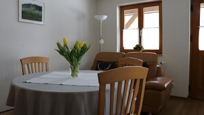 A dining area with a round table, chairs, a vase with flowers, a floor lamp, and a window with curtains. - Holiday Apartment 'Scharbachhof' with Mountain View, Shared Garden and Wi-Fi (Glottertal)