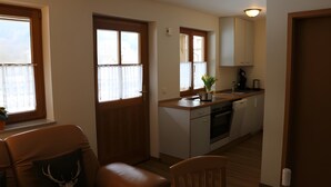 A compact kitchen with a dishwasher, a sink, and a window with curtains. - Holiday Apartment 'Scharbachhof' with Mountain View, Shared Garden and Wi-Fi (Glottertal)