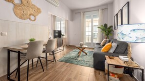 A modern living room with a dining area, a sofa, a TV, and a large window. - ‘Málaga Centro Bonito’ Apartment with Balcony, Wi-Fi and Air Conditioning (Málaga)