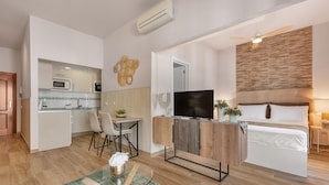 A compact living space with a kitchenette, a dining area, a TV, a bed, and a ceiling fan. - ‘Málaga Centro Bonito’ Apartment with Balcony, Wi-Fi and Air Conditioning (Málaga)