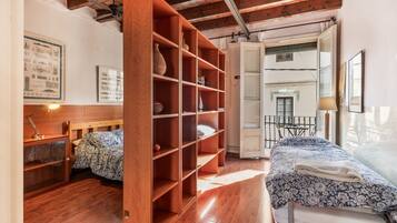 Una habitación con una cama de madera, un estante abierto grande, un escritorio con una lámpara y vistas al exterior.